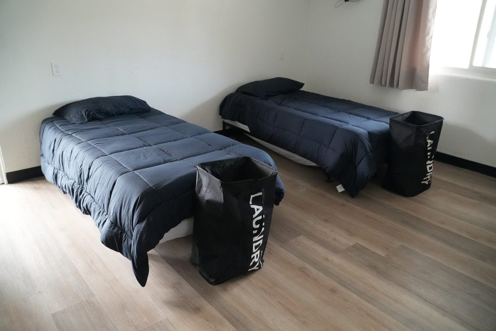 Two made beds beside a sunlit window in a HarborTAY room