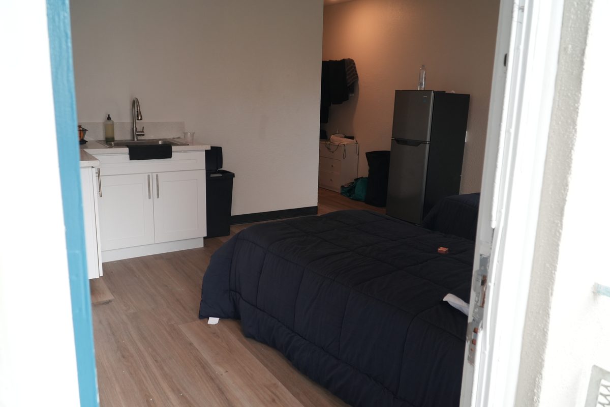 A HarborTAY studio unit with a kitchenette, refrigerator and made bed